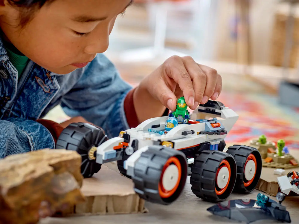 A child places a lego minifigure into the lego space explorer rover