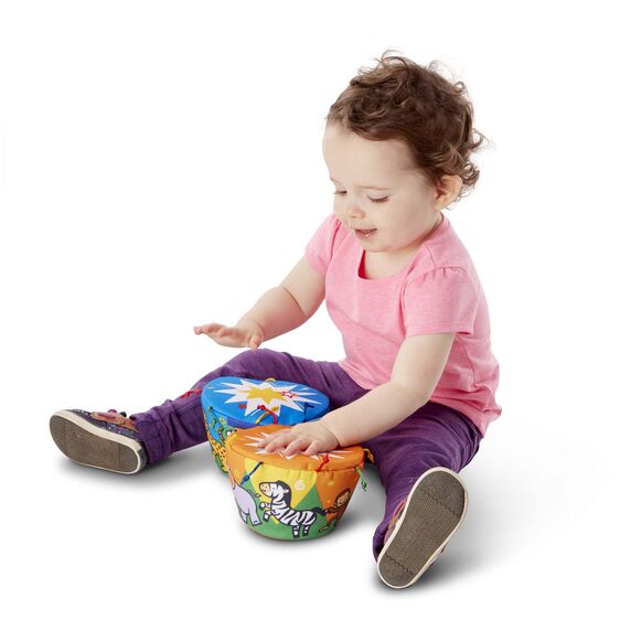 a smiling infant sitting up and interacting with a fun soft bongo toy